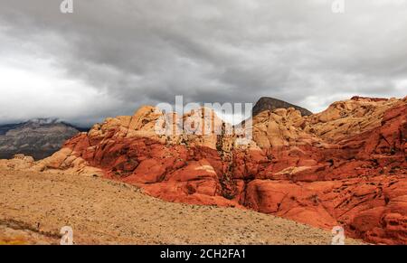 Des nuages orageux se ferment sur les collines Calico de la zone nationale de conservation de Red Rock Canyon, à 20 kilomètres à l'ouest de Las Vegas, NV, États-Unis. Le rouge dans les roches est causé par la percolation de l'eau souterraine à travers le fer oxydé dans les roches. Banque D'Images