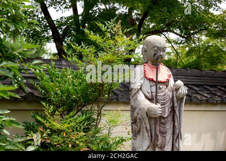 Arashiyama, Kyoto / Japon - 21 juin 2018 : des bavettes rouges ornent les statues dans les temples de Saga Arashiyama dans les collines occidentales de Kyoto. Banque D'Images