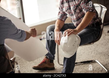gros plan photo rognée. concentrez-vous sur le casque blanc sur le genou du constructeur Banque D'Images