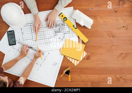 Vue de dessus des mains de deux ingénieurs ou architectes contemporains discuter de l'esquisse Banque D'Images