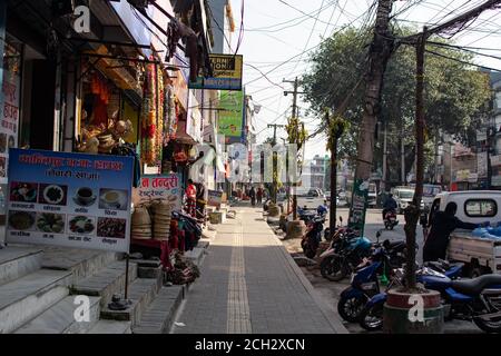 Pokhara, Népal - décembre 21 : des personnes non identifiées se promène sur le trottoir, entrent dans un magasin et font une moto dans la rue Pokhara, décembre 2019 Banque D'Images