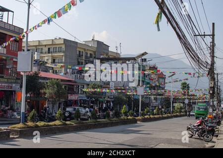 Pokhara, Népal - décembre 21: Des personnes non identifiées sur le trottoir comme un couple de voitures et une moto avec un conducteur non identifié conduit à Pokhara Banque D'Images