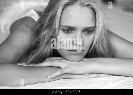 Dépression et solitude. Une jeune femme triste et pleine de pensée, au lit. Gros plan noir et blanc. Banque D'Images