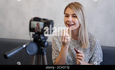 Un blogueur de beauté ou un blogueur de vidéo dit et montre aux abonnés comment faire le maquillage. La jeune femme peint les lèvres Banque D'Images