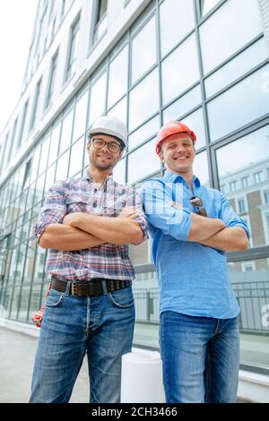 des ingénieurs talentueux et souriants se tenant devant la construction moderne. succès et concept de poste Banque D'Images