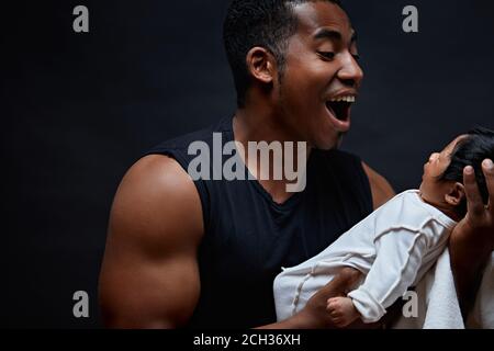 afro guy tente de taech son bébé pour parler, isolé fond noir. premiers sons. père pleurant des fils à sa fille de nouveau-né. gros plan portrait Banque D'Images