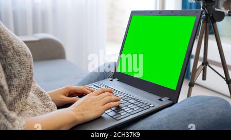 Femme blogueur travaillant sur ordinateur portable. Vue de l'appareil photo sur un trépied et un ordinateur portable avec écran couleur verte - vue rapprochée Banque D'Images