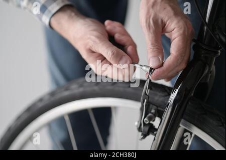 Un homme caucasien mature ajuste le frein de sa nouvelle bicyclette intérieur Banque D'Images