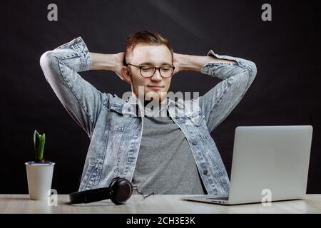 Étudiant au repos assis sur la chaise avec les bras levés après avoir travaillé dans l'ordinateur portable. Banque D'Images