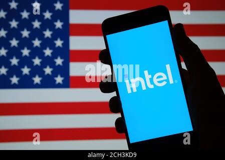 Stafford / Royaume-Uni - 2 septembre 2020 : nouveau logo Intel vu sur la silhouette du téléphone tenir à la main et drapeau américain flou sur fond flou. reb. Intel Banque D'Images