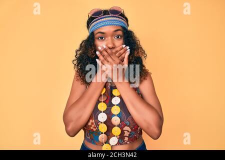 Une jeune femme afro-américaine portant le style bohème et hippie a choqué la bouche avec des mains pour erreur. Concept secret. Banque D'Images