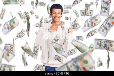 Jeune homme amérindien africain portant des vêtements décontractés émerveillé et souriant à l'appareil photo tout en présentant avec la main et en pointant avec le doigt. Banque D'Images