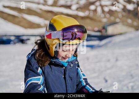 une fille avec un casque et des lunettes a l'air souriante sur un ski pente Banque D'Images