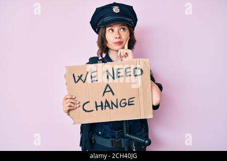 Jeune belle femme portant l'uniforme de police nous avons besoin d'une bannière de changement sérieux visage pensant à la question avec la main sur le menton, réfléchi à Banque D'Images