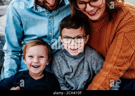 Gros plan de deux garçons heureux assis sur les genoux de leurs parents Banque D'Images