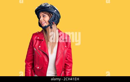 Jeune belle femme portant un casque de moto regardant de côté avec le sourire sur le visage, l'expression naturelle. Riant confiant. Banque D'Images