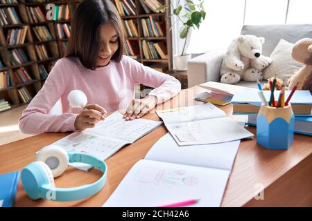 Jeune fille indienne souriante de l'école latine de la préadolescence étudiant à la maison assis au bureau. Banque D'Images