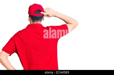 Jeune homme beau avec barbe portant l'uniforme de livraison en arrière-pensée le doute à la main Banque D'Images