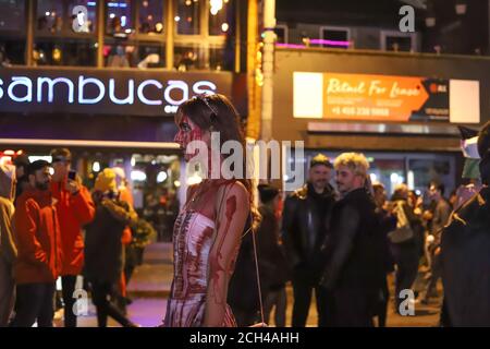 Halloween nuit carnaval . Rue de l'église, personnes marchant dans différents masques et costumes. Banque D'Images