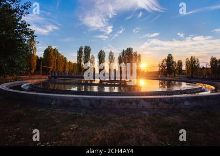 Usine moderne de traitement des eaux usées. Réservoir de purification des eaux usées rond au coucher du soleil Banque D'Images