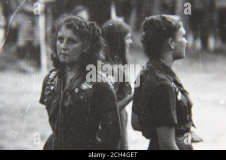 Belle photographie en noir et blanc vintage des années 70 des éclaireuses portant leur uniforme formel pendant le camping au camp de scouts. Banque D'Images