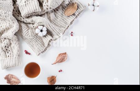 Composition d'automne. Une tasse de café, des fleurs de coton, des feuilles d'automne et un chandail pour femmes sur fond blanc. Flat lay, vue de dessus avec espace de copie. Banque D'Images