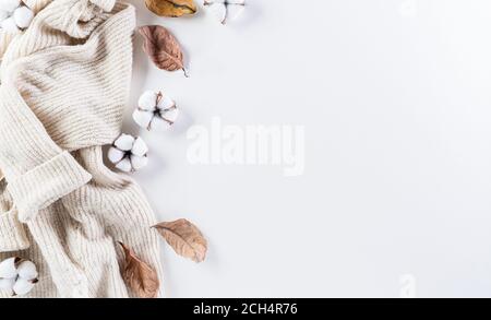 Composition d'automne. Fleurs de coton, feuilles d'automne et chandail pour femmes sur fond blanc. Flat lay, vue de dessus avec espace de copie. Banque D'Images