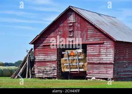 Lacon, Illinois, États-Unis. Une ancienne grange en bois rouge contenant un chariot de foin. La scène rurale provient du centre-nord de l'Illinois, dans la vallée de l'Illinois River. Banque D'Images