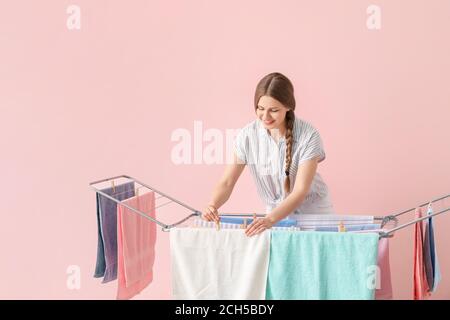 Femme qui pendait des serviettes propres sur le sèche-linge sur fond de couleur Banque D'Images