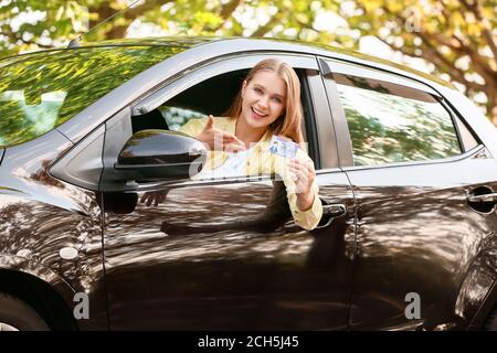 Bonne jeune femme après avoir réussi le test de permis de conduire Banque D'Images