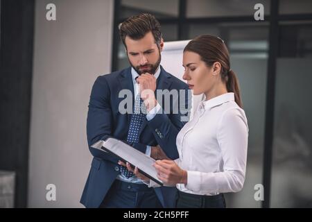 Femme à poil brun avec papiers de lecture de collègue à poil dur Banque D'Images