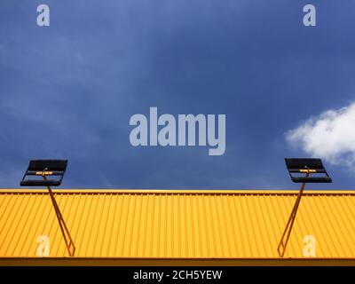 Paroi en tôle de zinc ondulée jaune vif et toit avec spot contre ciel bleu. Concentrez-vous sur le mur en tôle de zinc ondulé jaune. Banque D'Images