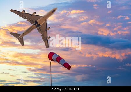 Windsock et jet plane dans le ciel lumineux de coucher de soleil. Le temps à l'aéroport concept Banque D'Images