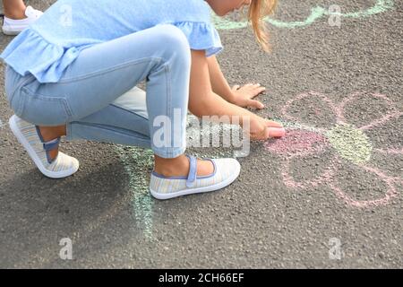 Petite fille dessin fleur avec craie sur asphalte Banque D'Images