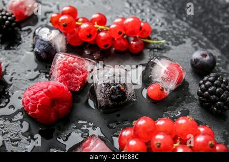 Glace avec baies congelées sur fond sombre Banque D'Images