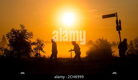 Laatzen, Allemagne. 14 septembre 2020. Les silhouettes des passants se démarquent du soleil levant et des champs de brouillard dans le Leinemasch, dans la région de Hanovre. Mi-septembre et températures comme en juillet ou août: Une zone de haute pression fournit le temps chaud à la fin de l'été en Allemagne. Credit: Julian Stratenschulte/dpa/Alay Live News Banque D'Images