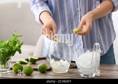 Femme qui fait un délicieux cocktail mojito à table Banque D'Images