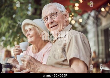 Couple moderne et âgé assis dans un café en plein air Banque D'Images