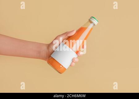 Main femelle avec bouteille de jus sur fond de couleur
