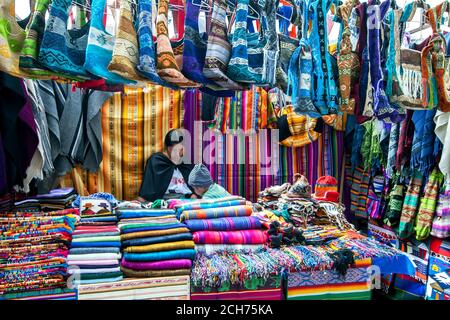 Une exposition colorée de produits textiles en vente sur le marché indien d'Otavalo au Pérou. Le marché vend une gamme d'artisanat et de textiles indiens. Banque D'Images