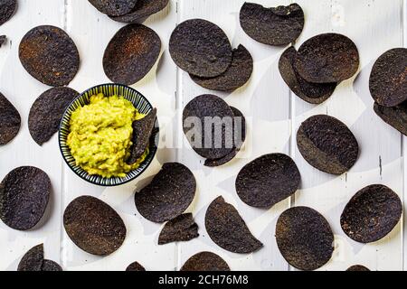 Croustilles noires avec sauce à l'avocat - guacamole, fond blanc. Banque D'Images