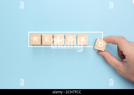 Homme main tenant cube en bois avec mot de redémarrage sur fond bleu. Main mettant cube en bois sur la barre de chargement de l'infographie virtuelle avec LE libellé DE RECHARGEMENT. Re Banque D'Images