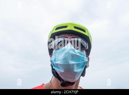 Cycliste adulte portant un casque de cyclisme, des lunettes de soleil et un masque facial, couvrant. Banque D'Images