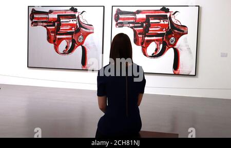 Une femme regarde LE CANON 1981 acrylique et écran à soie sur deux toiles, dans le cadre de l'exposition Andy Warhol à la Tate Gallery, Liverpool. Banque D'Images