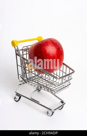 Pomme rouge fraîche placée à l'intérieur d'un mini panier sur un fond blanc dans une disposition simple et propre Banque D'Images