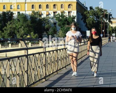 Séville, Espagne; 2 août 2020: Deux jeunes filles portant des masques se baladent dans les rues désertes de Séville pendant la pandémie du coronavirus Banque D'Images