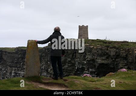 Les visiteurs se promondent le long des falaises au-dessus de la mer à Marwick Head à Orkney, où se dresse la tour construite pour honorer la mémoire de Lord Kitchener. Banque D'Images