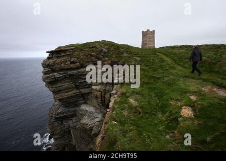 Les visiteurs se promondent le long des falaises au-dessus de la mer à Marwick Head à Orkney, où se dresse la tour construite pour honorer la mémoire de Lord Kitchener. Banque D'Images