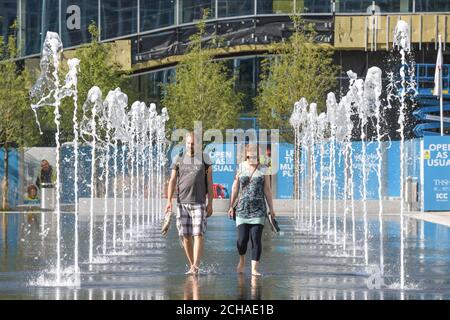 Birmingham West Midlands, 14 septembre 2020. Un couple marche pieds nus à travers les fontaines de Centenary Square, Birmingham profitant du soleil chaud du matin sur ce qui est prévu pour être le jour le plus chaud du mois. La plupart des gens observaient la «règle des 6», mais un groupe de personnes âgées a dépassé 8 personnes comme on leur a montré la mairie de Victoria Square. Birmingham se prépare à entrer dans un confinement local mardi en raison d’une augmentation des cas de coronavirus. La ville interdira aux gens d'entrer dans d'autres ménages à moins d'être exemptés. Crédit : arrêtez Press Media/Alamy Live News Banque D'Images