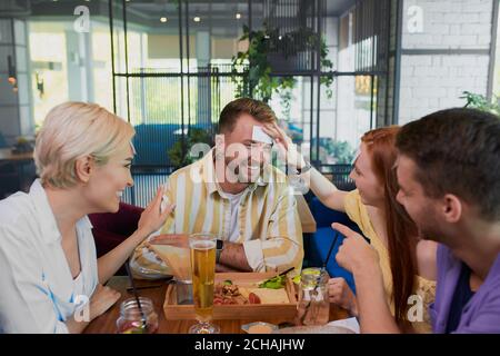 Les amis jouent ensemble qui je suis dans le café, temps de loisirs. Humour, concept de divertissement Banque D'Images